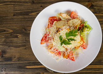 Caesar salad with croutons, cheese, eggs, tomatoes and grilled chicken on wooden tabel. with copy space. top view