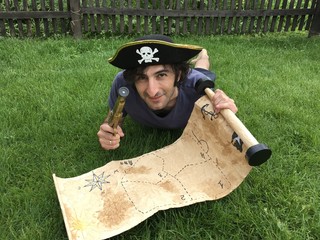 Pirate with a treasure map lying on the grass