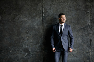 Portrait of stylish male dressed in a suit over grey background