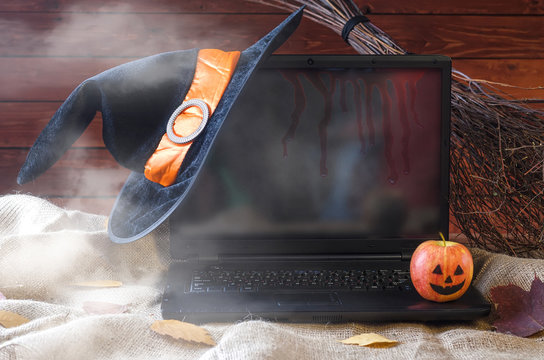 The concept of Halloween: a laptop, a witch hat and a broom, free space for your advertising.