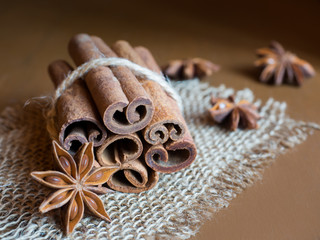 Obraz na płótnie Canvas Cinnamon sticks linked by a string on burlap Brown wooden background