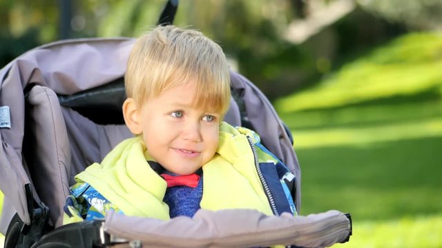 Happy joy caucasian Child, kid toddler , little baby boy smiling and clapping in stroller . Childhood dreams and memories. Slow motion