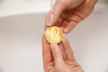 bitcoin. man washes gold coins. Concept money laundering, wash water