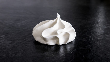 Sweet white meringue is isolated on a dark background.