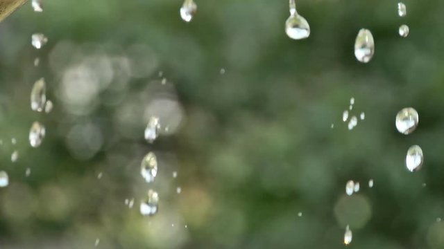 Slow motion of a drop of water flowing down from a stone statue