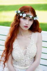 Portrait of a beautiful redheaded girl with long curly hair. Bride. With handmade jewelry on the hair. Hair to the waist. Very long red hair. The average plan