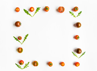 Cherry tomatoes and rocket salad leaves frame on white background. Flat lay