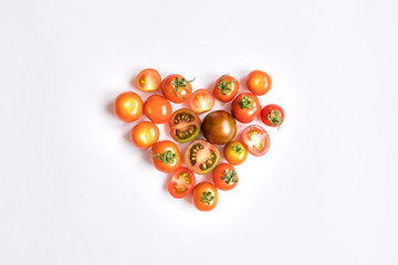 Cherry tomatoes in a heart shape on white background. Flat lay