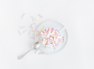 Colorful light marshmallows in a cup on white background. Top view, flat lay