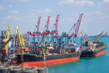 Tugboat assisting container cargo ship to harbor quayside.