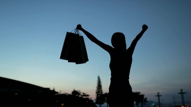 Woman holding up paper bags in slow motion