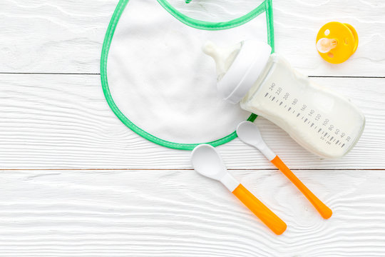 preparation of mixture baby feeding with infant formula powdered milk in bottle with bib on white background top view mock-up