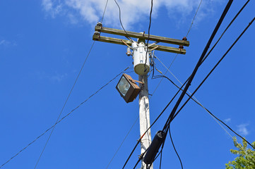 Telephone pole with lots of wires, cables, and a street light