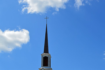 Tall church steeple with a Christian cross and a bell tower