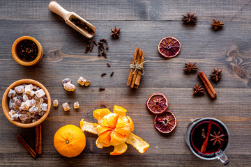 Hot mulled wine or grog cooking for new year celebration with oranges and spices ingredients on wooden background flat lay