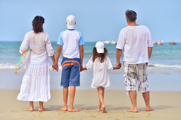 family standing on sandy beach