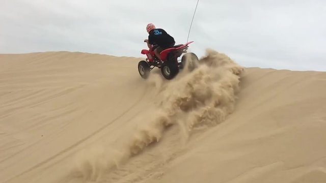 Ragazzo con quad su dune di sabbia, slowmotion