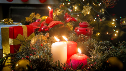 Beautiful Advent wreath with burning candles against decorated Christmas tree