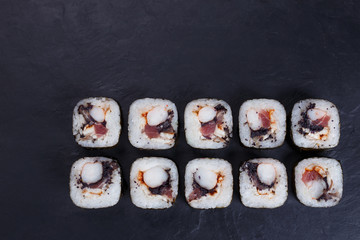 Japanese food, sushi restaurant. Delicious futomaki sushi rolls with  black caviar, tuna and prawn served on black slate with free space for text design, flat lay