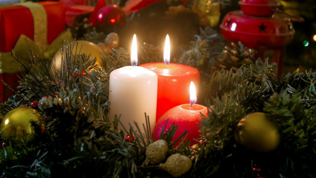 Closeup image of red and white burning Christmas candles on advent wreath