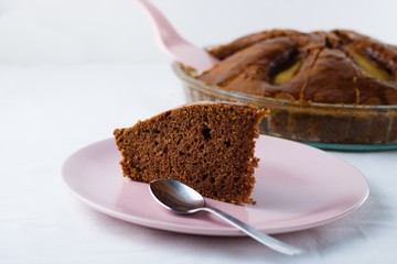 Slice of pear pie on pink plate with whole baked pie in background
