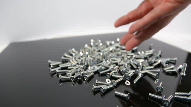 Close-up of heap of bolts, screws and nuts falling on neutral background in studio shot