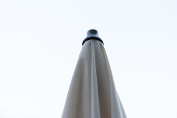 closed parasol sun umbrella with clean background low angle view beige colour