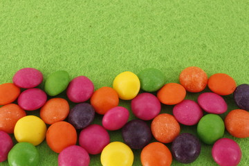 Multicolored sweets lie on a green surface