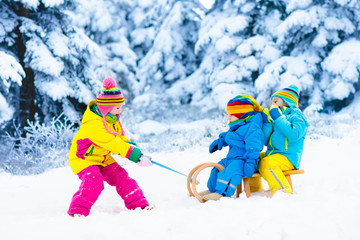 Kids on sleigh ride. Children sledding. Winter snow fun.