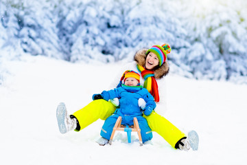 Mother and baby on sleigh ride. Winter snow fun.