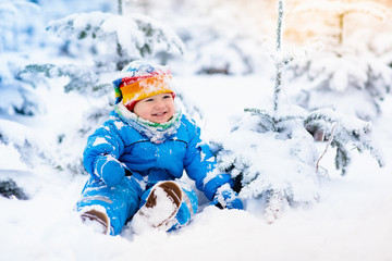 Fototapeta na wymiar Baby playing with snow in winter. Child in snowy park.