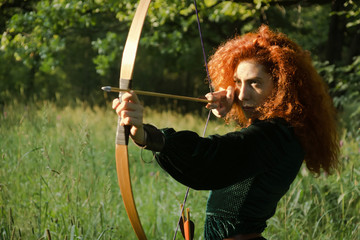 Red haired girl shoots from the bow