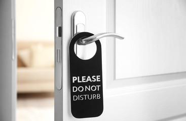 Fototapeta premium Open door with sign PLEASE DO NOT DISTURB on handle at hotel