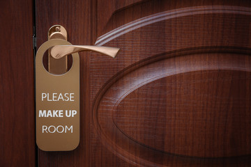 Closed door with sign PLEASE MAKE UP ROOM on handle at hotel