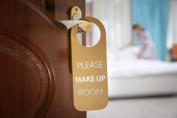Obraz premium Open door with sign PLEASE MAKE UP ROOM on handle at hotel
