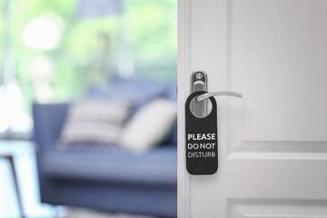 Obraz premium Open door with sign PLEASE DO NOT DISTURB on handle at hotel