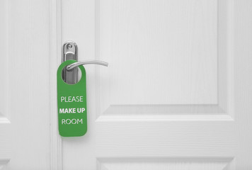 Naklejka premium Closed door with sign PLEASE MAKE UP ROOM on handle at hotel