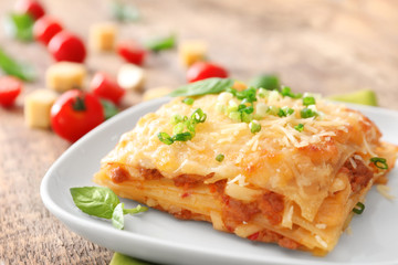Plate with tasty lasagna on table