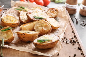 Board with delicious rosemary potatoes on table