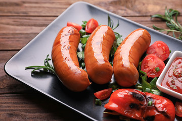 Grilled sausages served with vegetables and sauce on plate