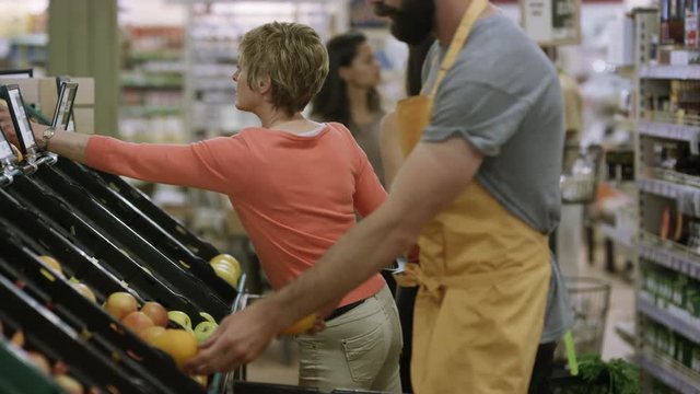  Friendly worker in a supermarket assisting lady buying groceries