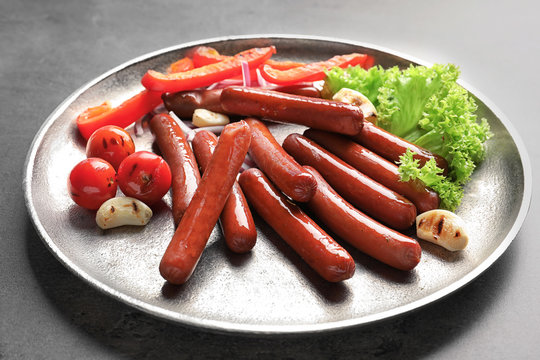 Grilled sausages served with vegetables on metal plate