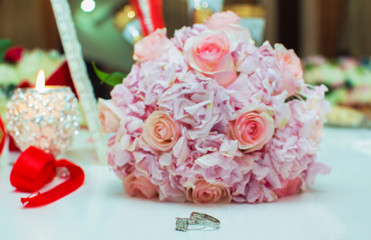Wedding bouquet of pink roses and wedding rings on a wooden table. Copy space. The concept of a wedding, party, love and family and rings