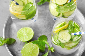 Obraz premium Delicious refreshing water with cucumber in glasses on metal tray