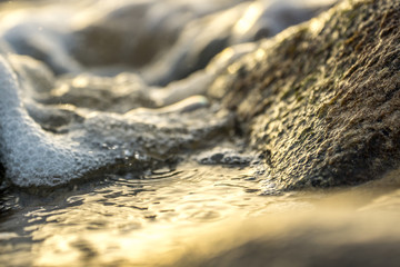 sunrise on a beach with waves and stones in the water - 174347623