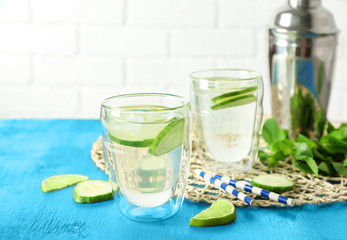 Delicious refreshing water with cucumber in glasses on table
