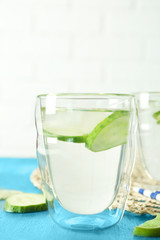 Delicious refreshing water with cucumber in glass on table
