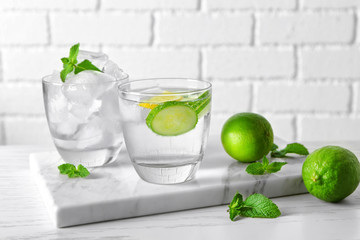 Delicious refreshing water with cucumber in glass on board