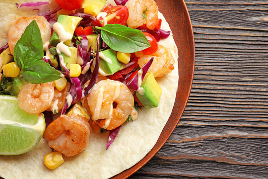 Plate with delicious shrimp taco on wooden table