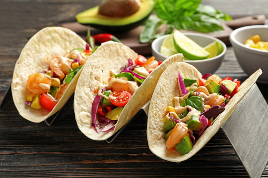 Holder with delicious shrimp tacos on wooden table